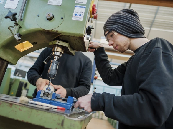 Zwei Azubis arbeiten zusammen an einer großen Maschine 