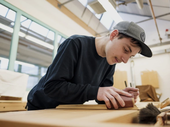Schreiner-Azubi schleift an Stück Holz ab