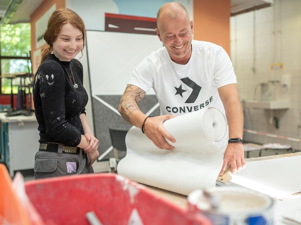 Auszubildende und Ausbilder beim Tapezieren