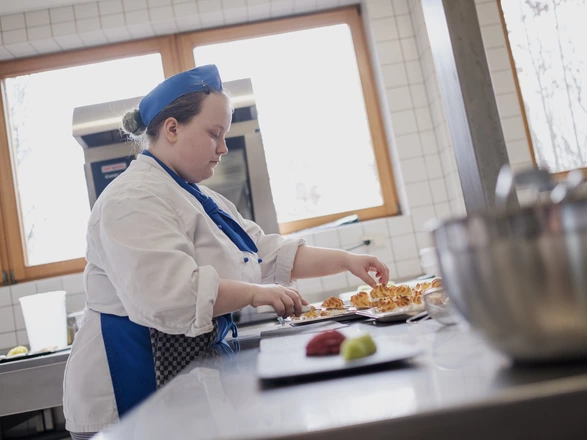 Eine junge Köchin richtet Teller an