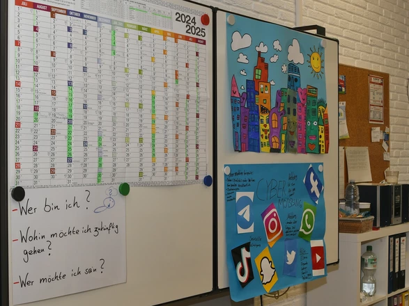 Bild einer Pinnwand im Schulforum mit einem Kalender und Projektpostern.