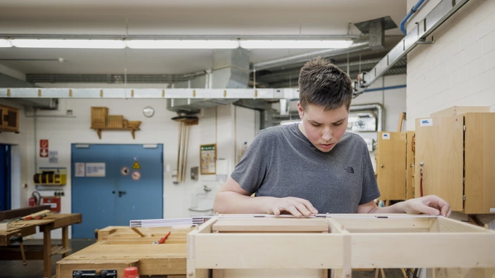 Auszubildender in einer Schreinerei arbeitet mit Holz