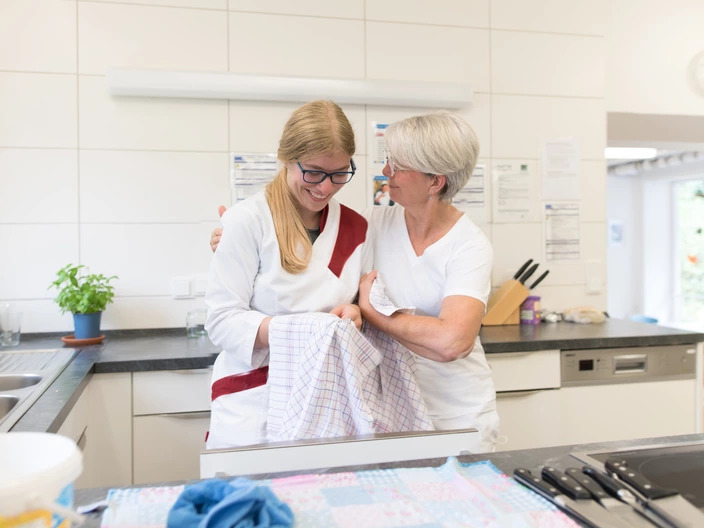 Auszubildende und Ausbilderin sortieren Besteck in der Küche