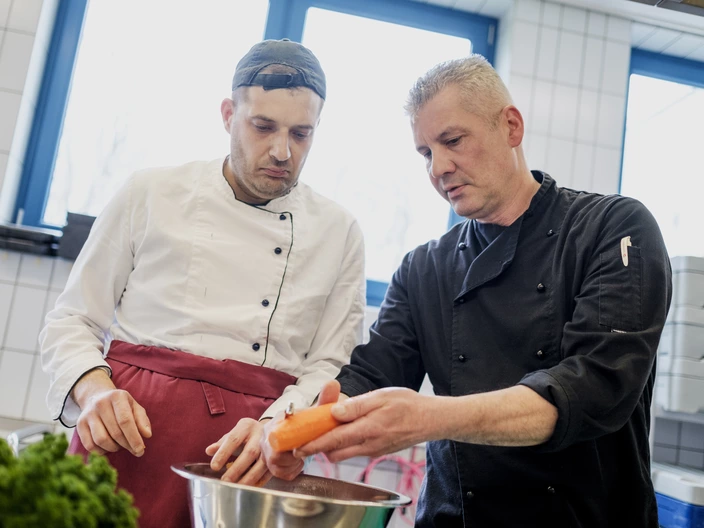 Auszubildender und Ausbilder schälen Gemüse