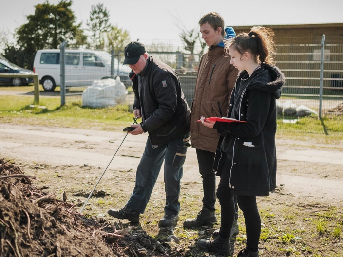 Zwei Auszubildende mit Ausbilder testen den Boden